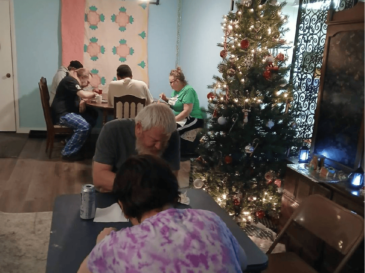 People gathered around tables by Christmas tree
