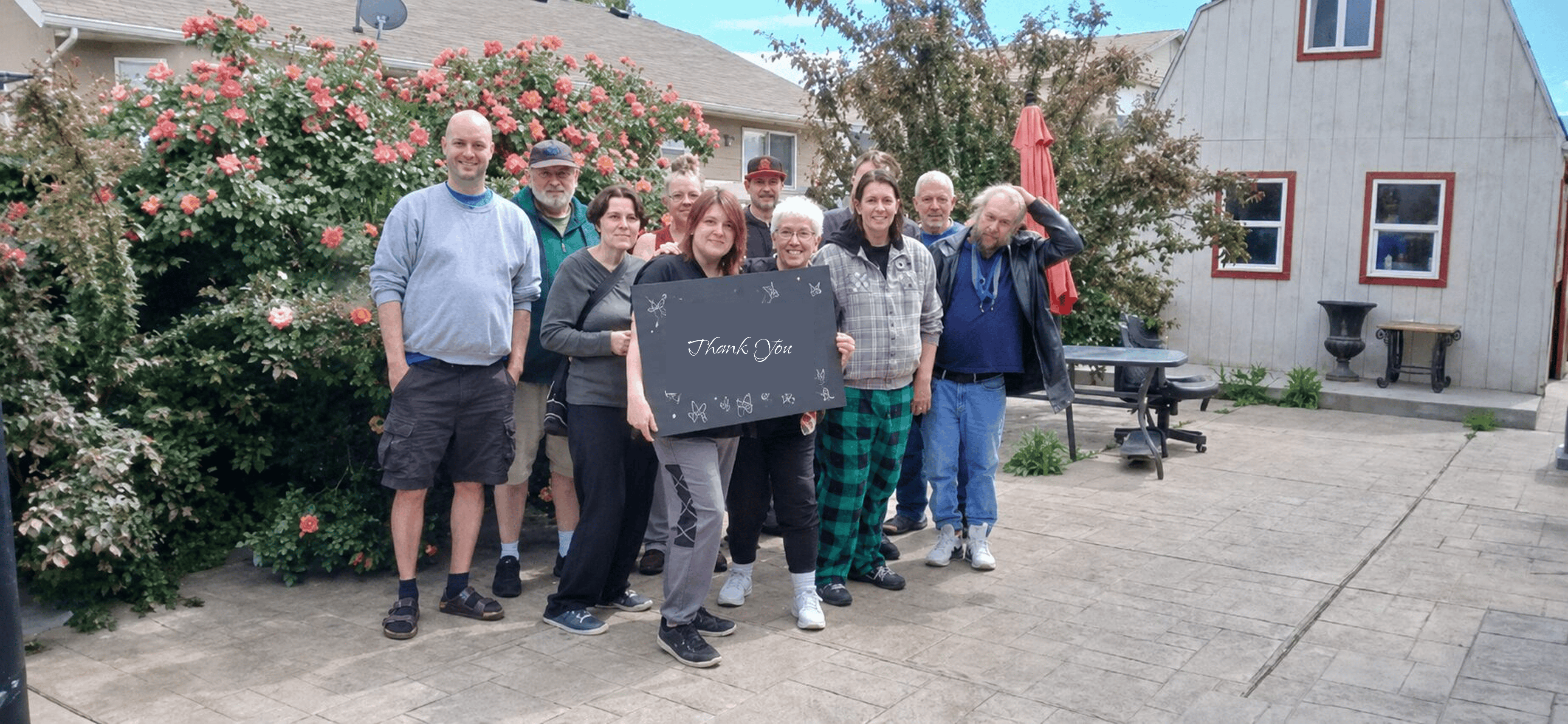 Group of people holding thank-you sign in backyard
