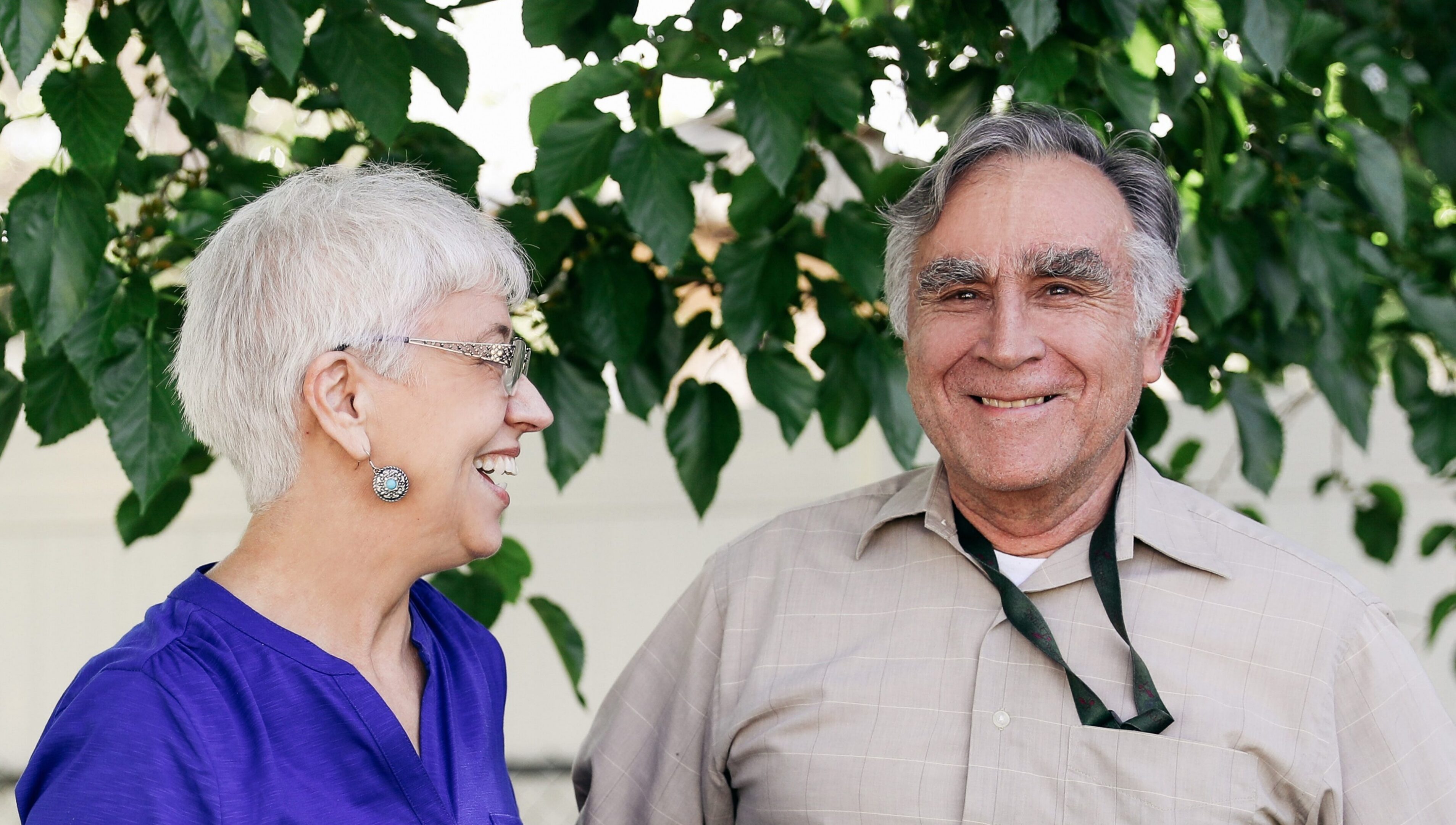 Smiling senior couple standing outdoors under tree