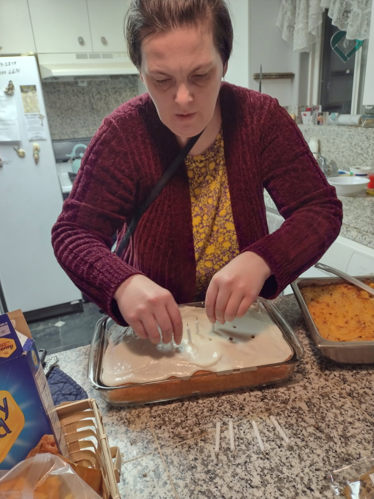 Person frosting rectangular cake in home kitchen