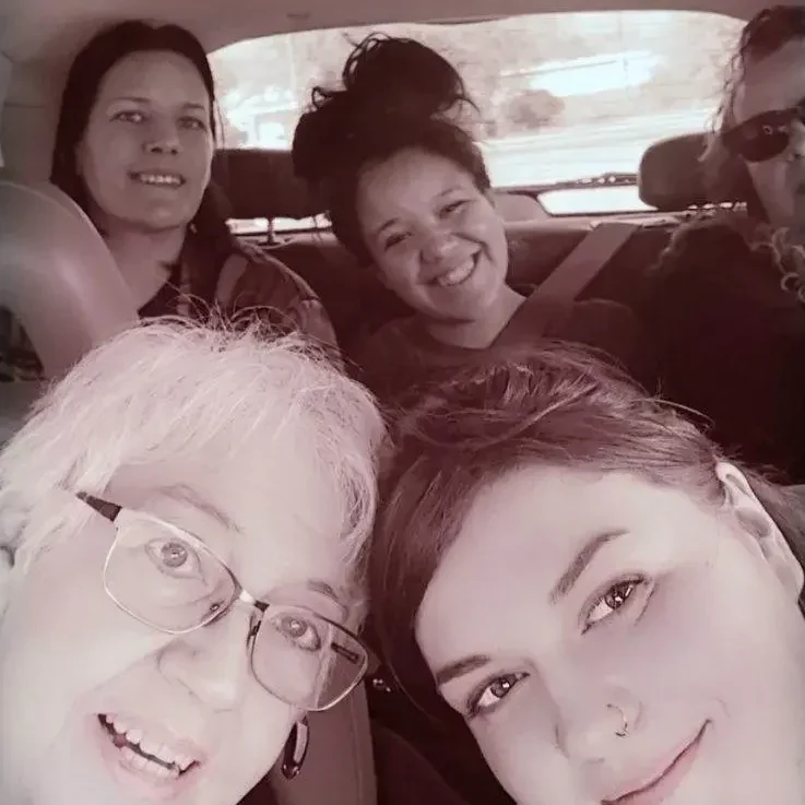 Five people smiling inside a car selfie