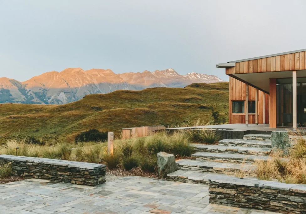 Modern house with mountainous landscape at sunset.