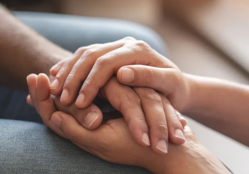 Hands gently holding each other, showing support.